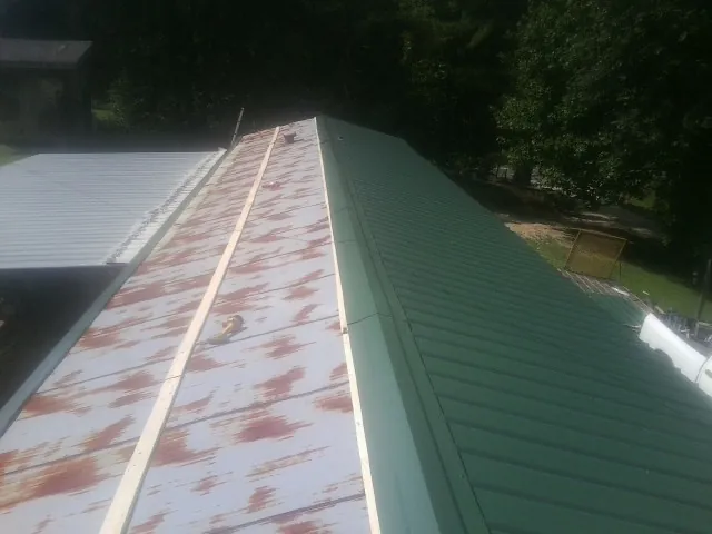 Old rusted panels beside newly installed green metal roofing — Wind Damage Roof Repair by Roofing Brothers in Channelview