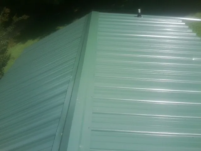 New green metal panels meeting at the ridge of a roof — Flat Roof Repair work by our crew in Channelview
