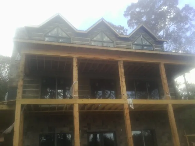 Dormers and porch framing on a large log home under construction — Roof Coating work by our crew in Channelview