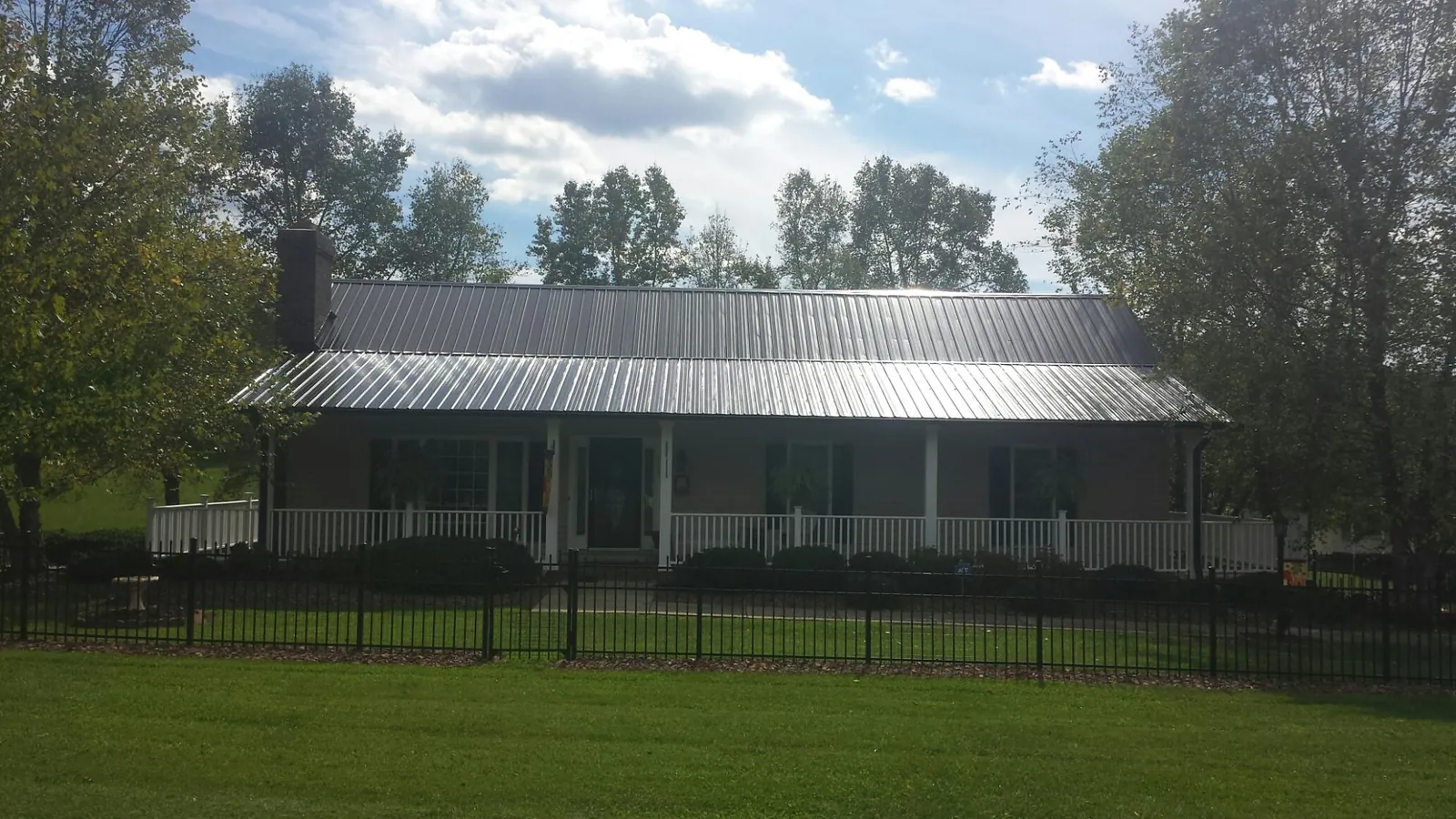 Gray metal roof on a brick ranch with a full width front porch — Gutter Guard Installation work by our crew in Channelview