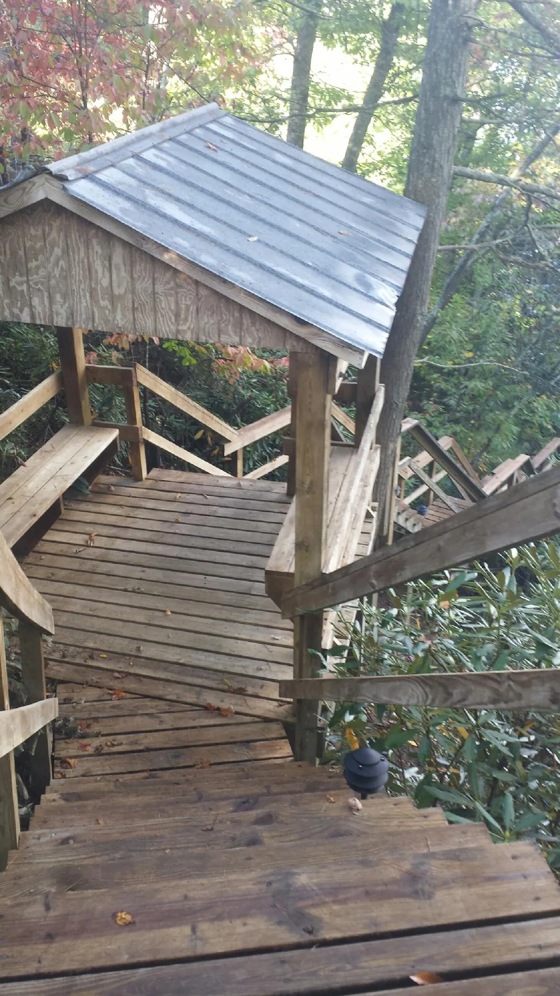 Metal roofed shelter over wooden steps on a wooded walkway — Skylight Repair & Installation work by our crew in Channelview