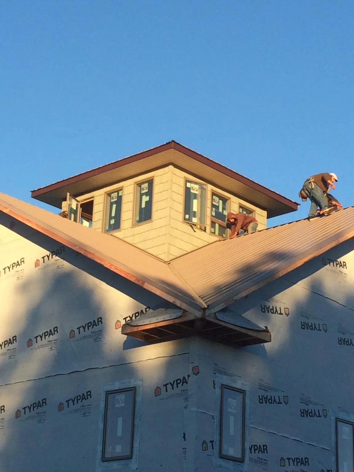 Roofers working around a rooftop cupola on a new metal roof at sunset — Roof Waterproofing in Channelview by Roofing Brothers